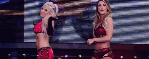 two female wrestlers are dancing in front of a large screen .