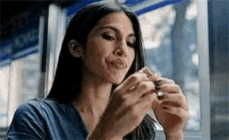 a woman is sitting at a table eating a hamburger and making a funny face .