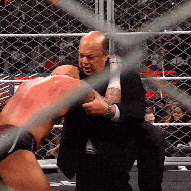 a man in a suit is holding another man 's head in a cage