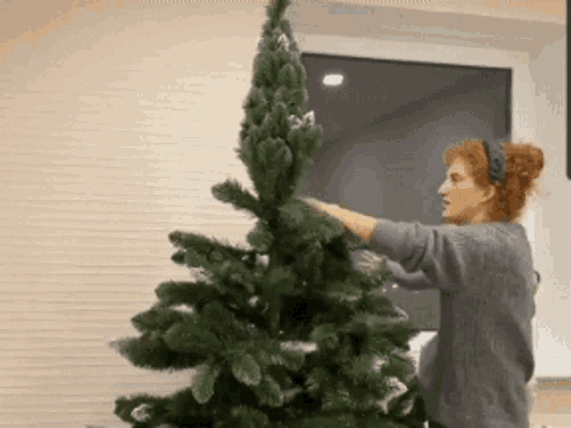 a woman is decorating a christmas tree with snow on it