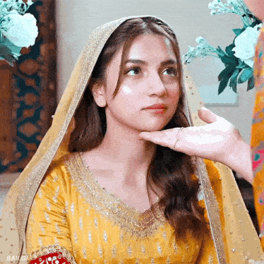 a woman in a yellow dress has a hand on her chin