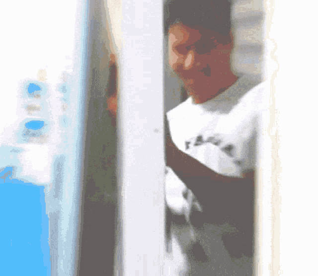 a man in a white shirt with the word fear on it stands in a doorway