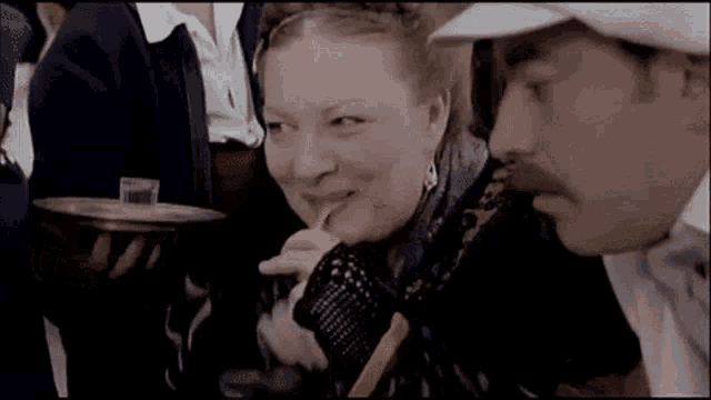 a man and a woman are sitting next to each other in a crowd .