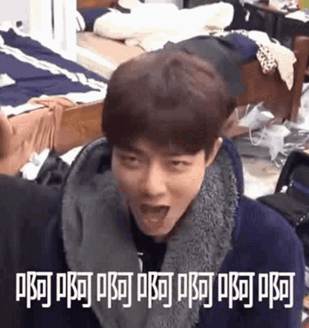 a young man is making a funny face with his mouth open in a messy room .
