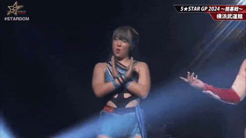 a woman in a blue and black outfit is standing on a stage with her arms crossed .