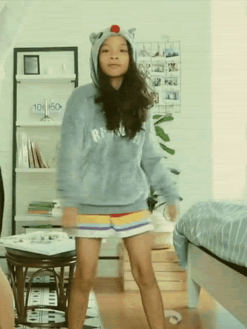a girl wearing a cat hooded sweatshirt and shorts is dancing