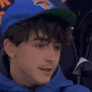 a young man wearing a green hat and a blue jacket looks up