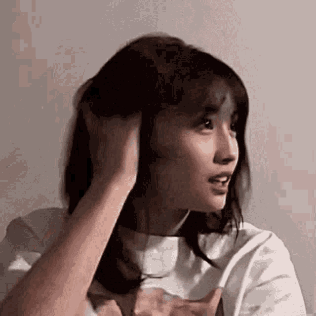 a woman is holding her hair in her hands and looking at the camera .