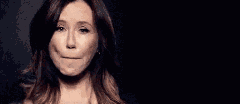 a woman is blowing a kiss into a microphone in a black background .