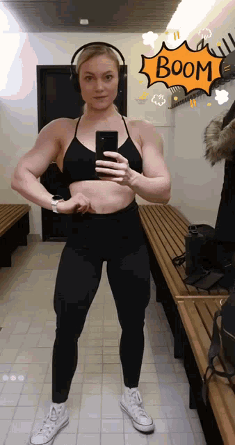 a woman is taking a picture of herself in a locker room with a boom sticker