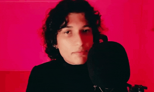 a young man with curly hair is standing in front of a microphone .
