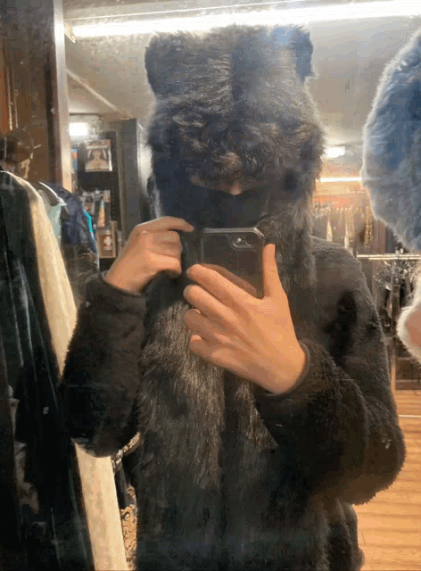 a person taking a picture of themselves in a mirror wearing a fur hat