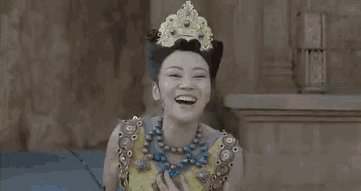a woman in a costume with a crown on her head is dancing in front of a stone wall .