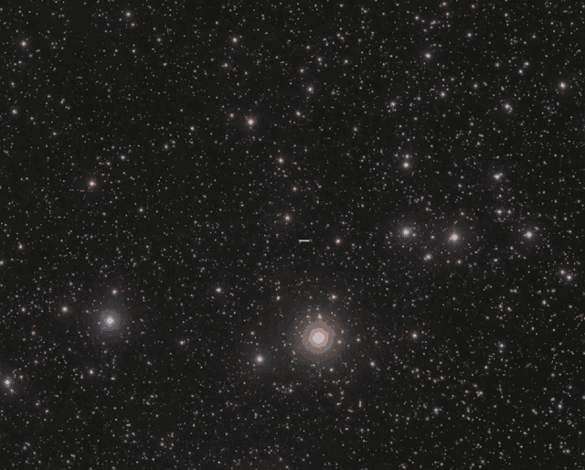 a cluster of stars in the night sky with a small white object in the middle