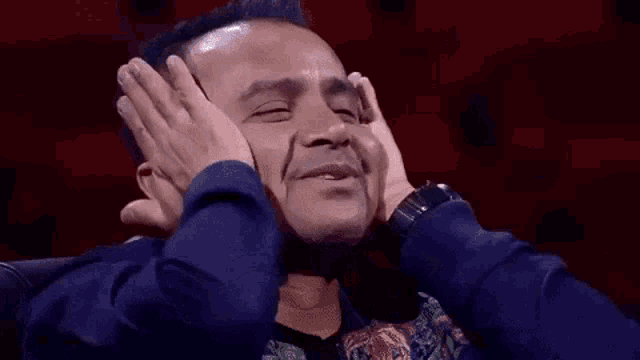 a man is covering his mouth with his hands and the word wad is written on the screen .