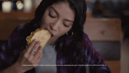 a woman is eating a taco with a limited time offer