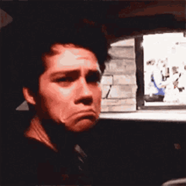 a close up of a man making a sad face in a car