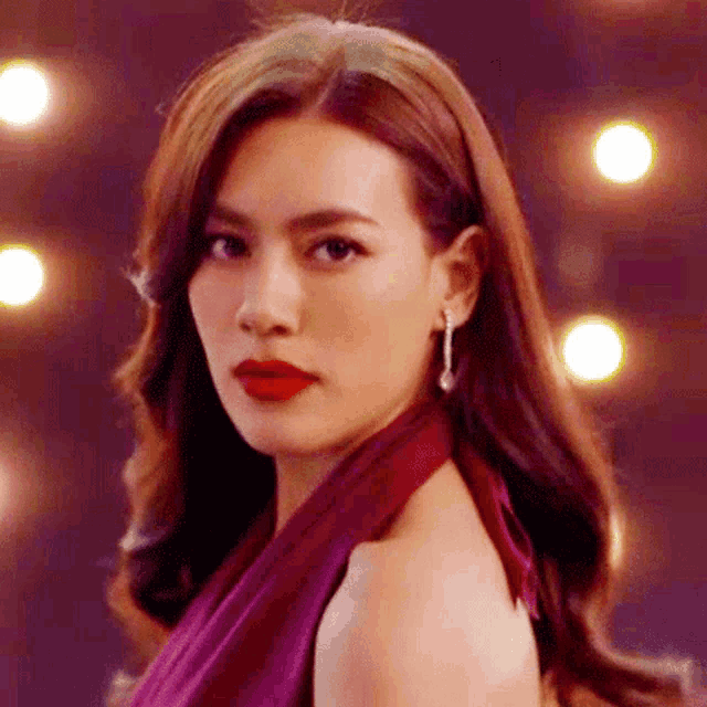 a woman in a purple dress with red lipstick and earrings