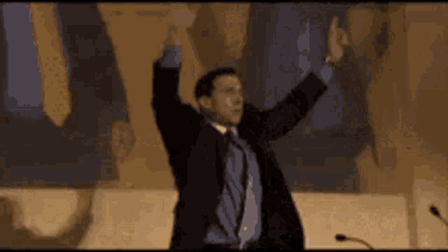 a man in a suit and tie is standing with his arms in the air .