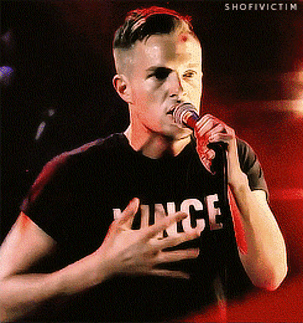 a man singing into a microphone with a shirt that says vince on it