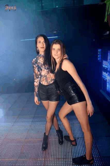 two women posing for a picture with the word spi3 on the bottom right