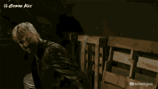 a man in a leather jacket is standing in a dark room with a youtube originals logo in the corner