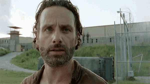 a man with a beard is standing in front of a fence