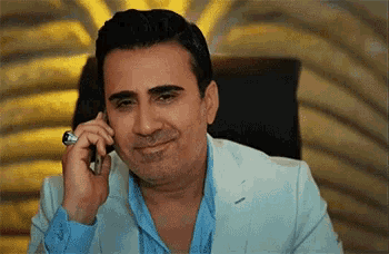 a man in a suit and blue shirt is talking on a cell phone