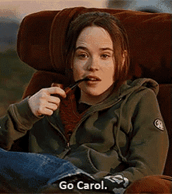 a woman is sitting in a chair smoking a pipe and says go carol