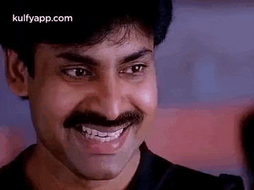 a man with a mustache is smiling and making a face .