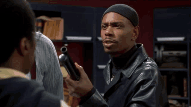 a man in a black leather jacket holds a gun in his hand