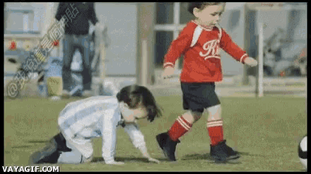 two young boys are playing soccer on a field and one is wearing a red jersey with the letter k on it .