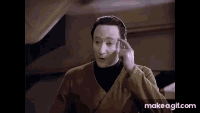 a man with white paint on his face is making a funny face with his finger .