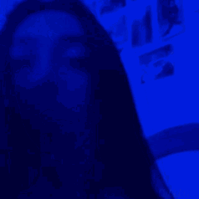 a person is standing in a dark room with a blue light behind them