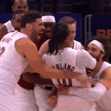 a group of basketball players are hugging each other and one of them has the name arland on his back