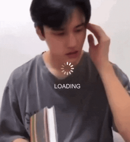 a man in a gray shirt is holding a book while a loading screen is displayed on his face .