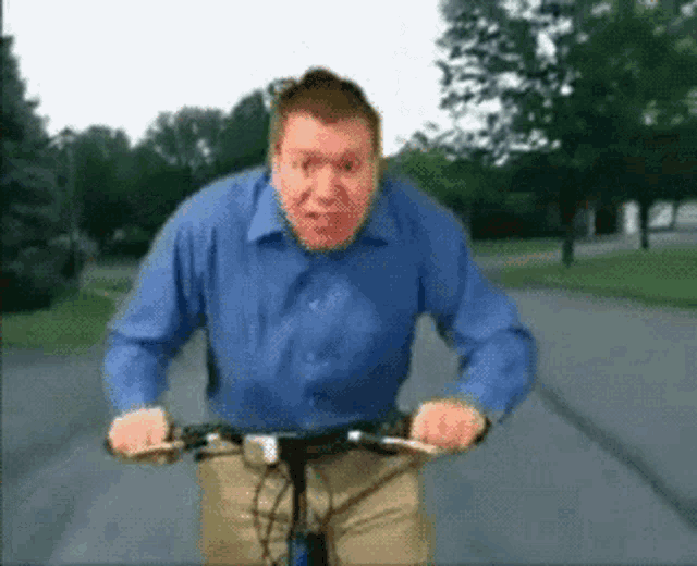 a man in a blue shirt is riding a bicycle down a road