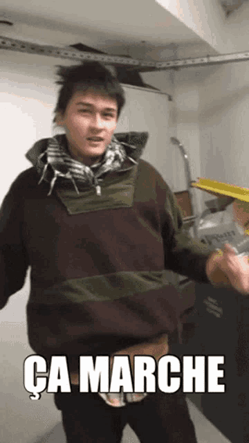 a man in a brown and green sweater with the words ca marche written on the bottom