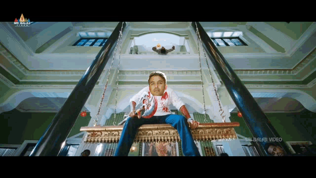 a man is sitting on a swing with a balaji video logo on the corner