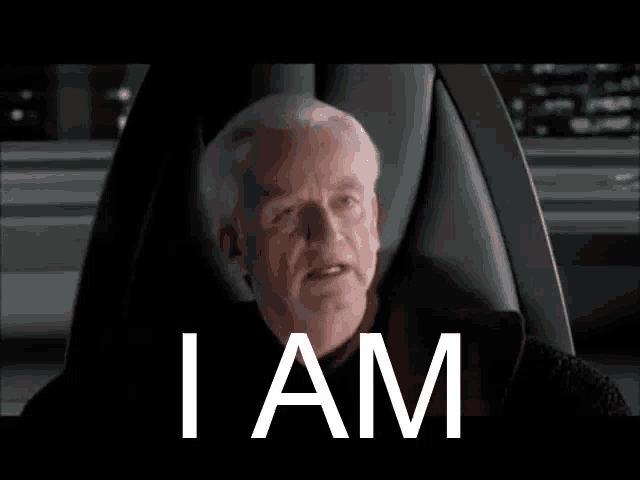 a man is sitting in a chair with the words `` i am '' written on the screen behind him .