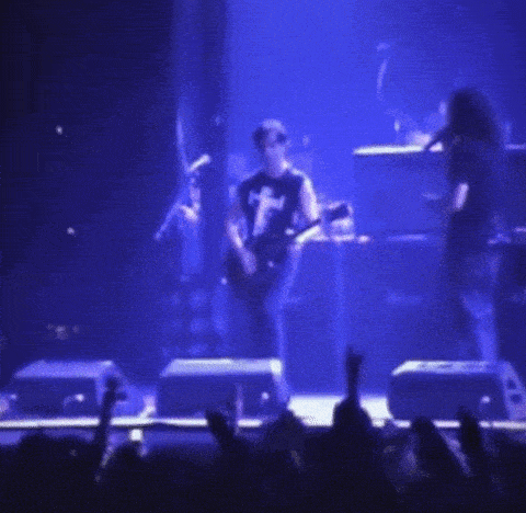 a man playing a guitar on a stage with a crowd behind him