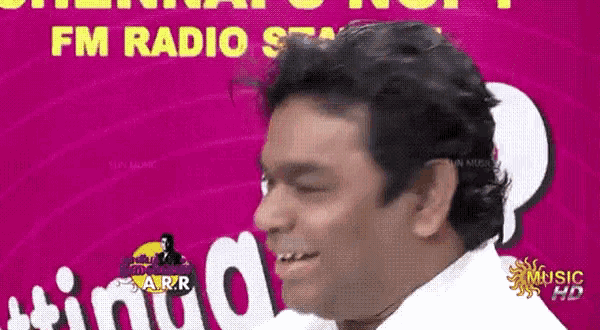 a man is smiling in front of a pink background that says fm radio