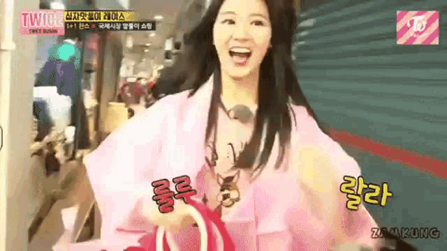 a woman in a pink robe is smiling and holding a bag .