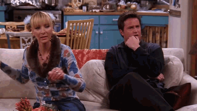 a man and a woman are sitting on a couch with their arms crossed