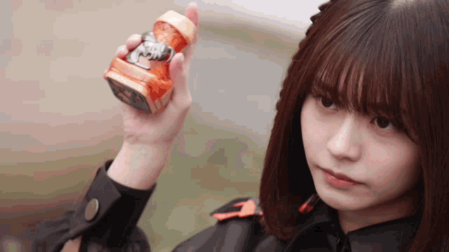 a girl is holding a small object in her hand that says ' a ' on it