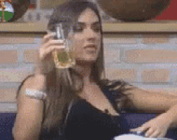 a woman in a black dress is sitting on a couch holding a glass of beer .