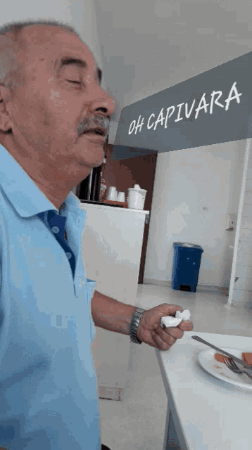a man with a mustache is standing in front of a sign that reads oh capivara