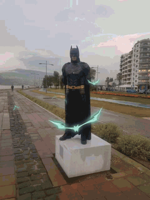 a statue of a man in a batman costume stands on a pedestal
