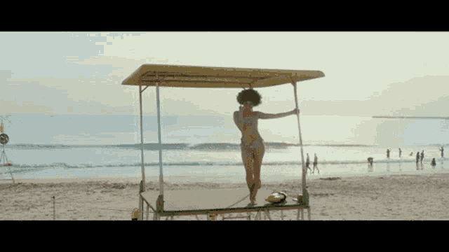 a woman in a pink bikini is standing on a green platform on the beach