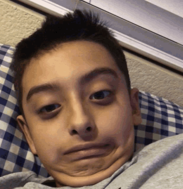 a young boy making a funny face while laying on a bed